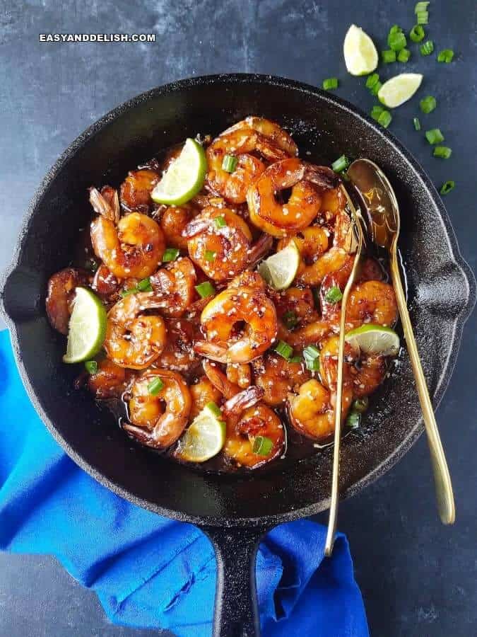 butter shrimp in a skillet with lime and green onions on the side