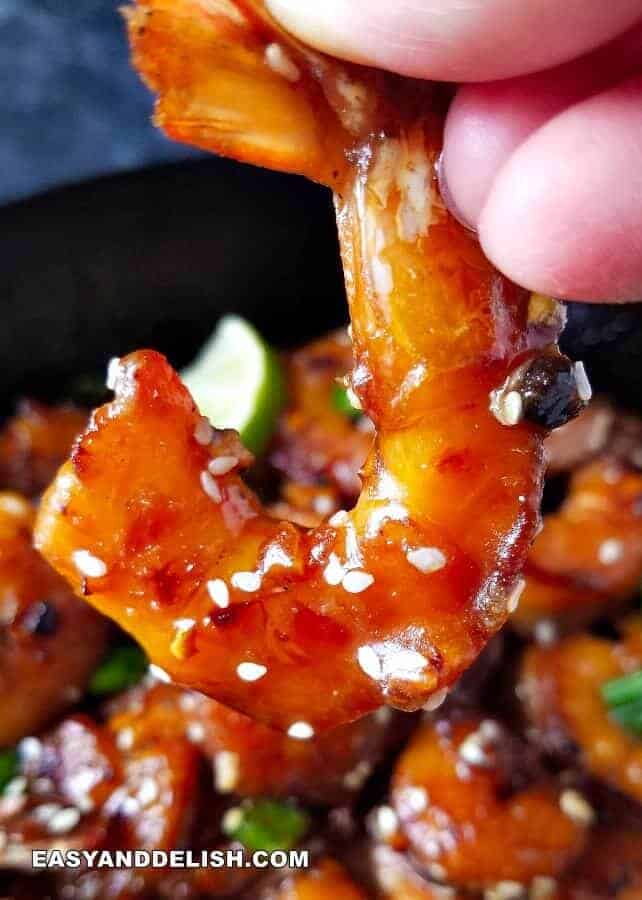 close up imahe of garlic butter shrimp being held by a hand