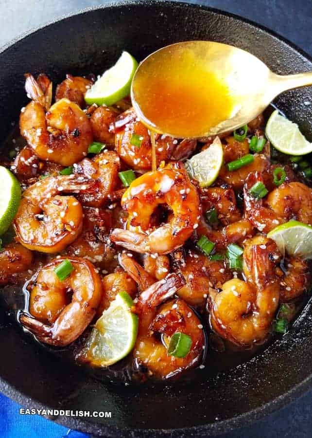 A skillet filled with shrimp and lime wedges