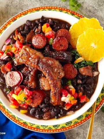 a bowl of feijoada topped with some traditional sides