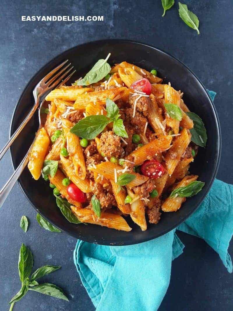 pasta with basil on top and cutlery on the side