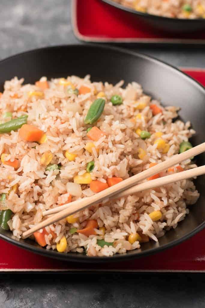 a bowl of rice with vegetables and chopsticks