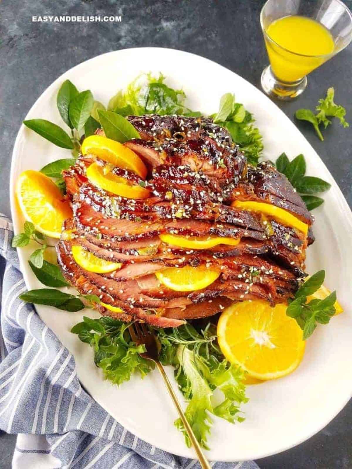 slow cooker ham with orange brown sugar glaze and orange slices served in a platter.