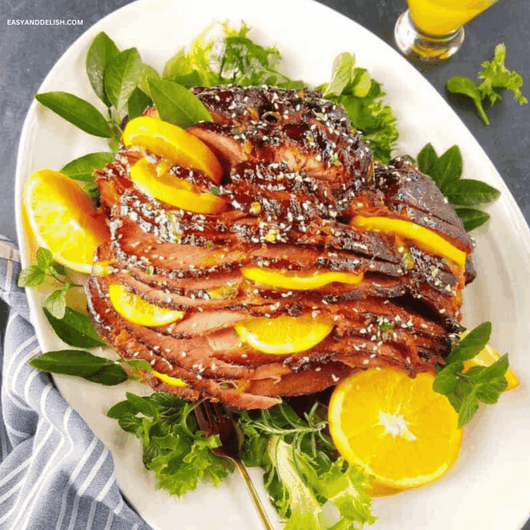 Slow cooker ham with brown sugar glaze and orange slices in a platter.