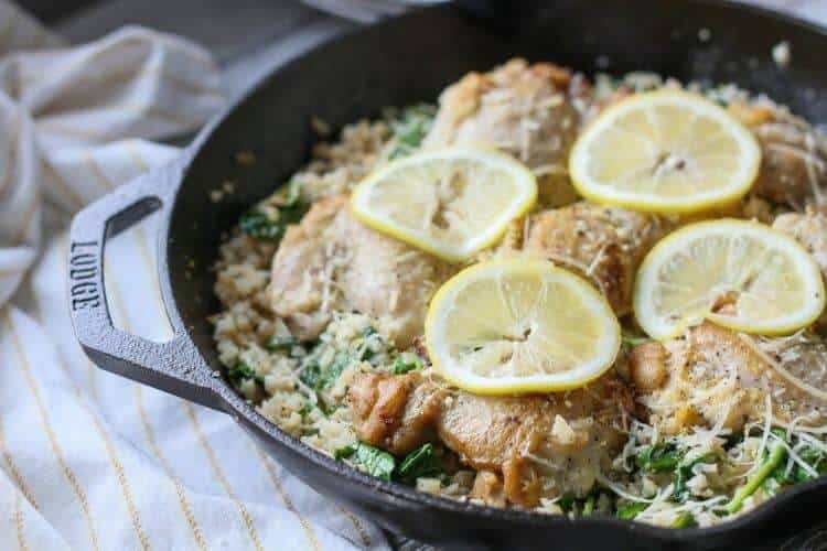 a skillet of chicken with lemon slices on top