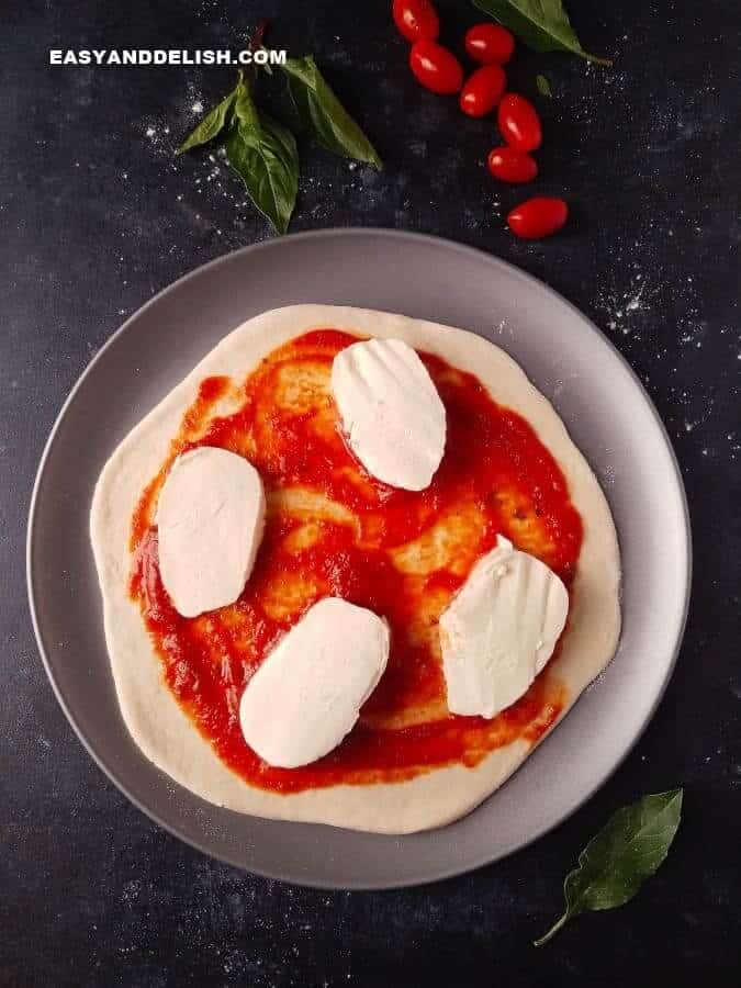 pizza crust topped with tomato sauce and fresh mozzarella cheese