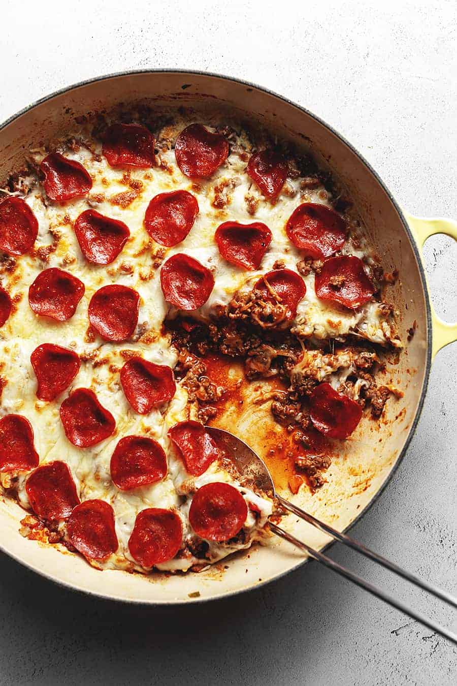 keto pepperoni pizza in a skillet with a spoon on the side as one of the easy oen pot meals