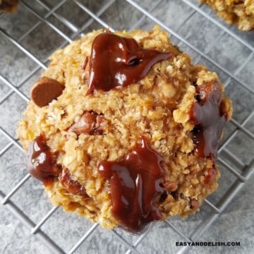 Close up of one of several gluten-free oatmeal chocolate chip cookies on a rack.