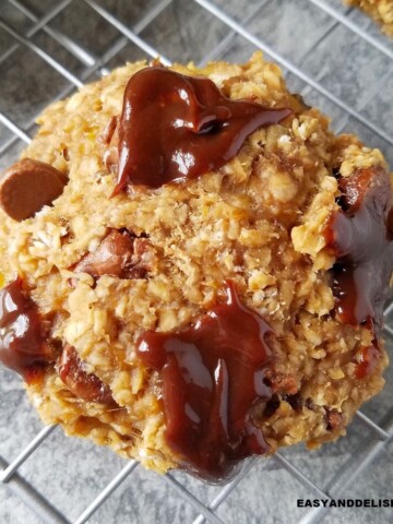 Close up of one of several gluten-free oatmeal chocolate chip cookies on a rack.