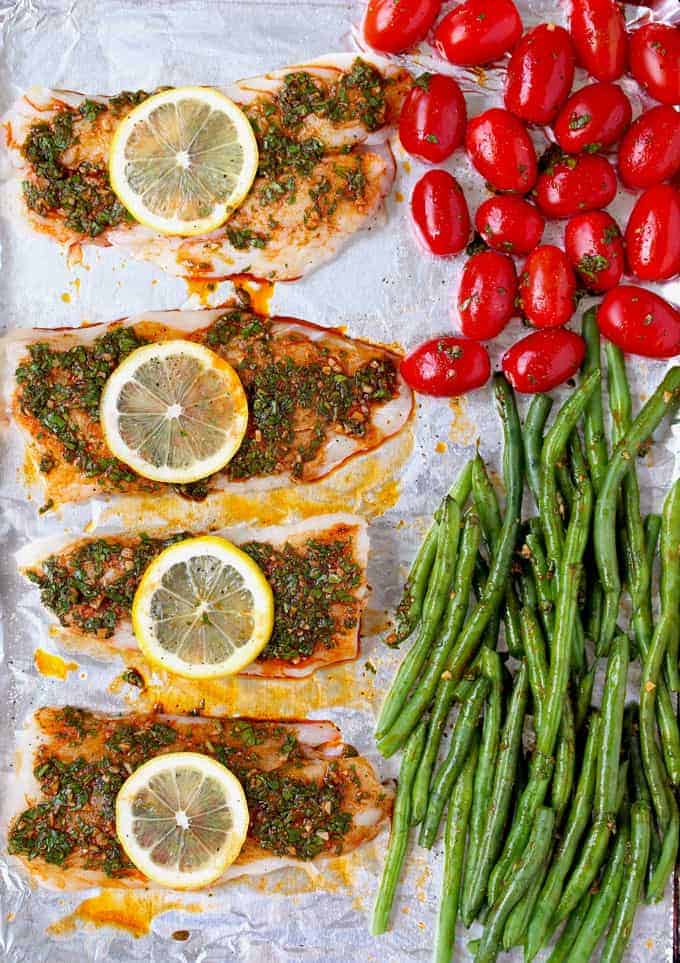 cod with sauce and lemon slices plus veggies in a pan