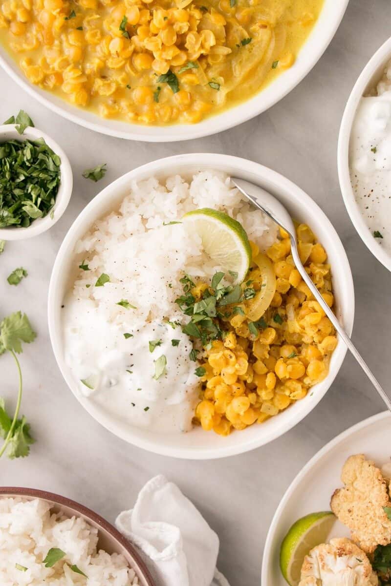 yellow dal with rice in a bowl with garnishes on the side as one of healthy one pot emals