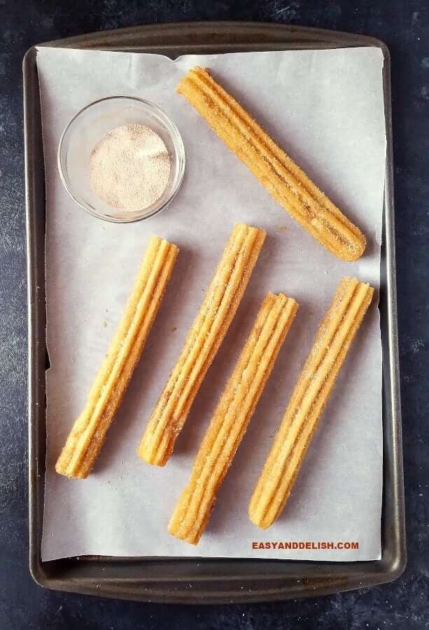 churros fritos em uma assadeira com uma mistura de canela e acucar