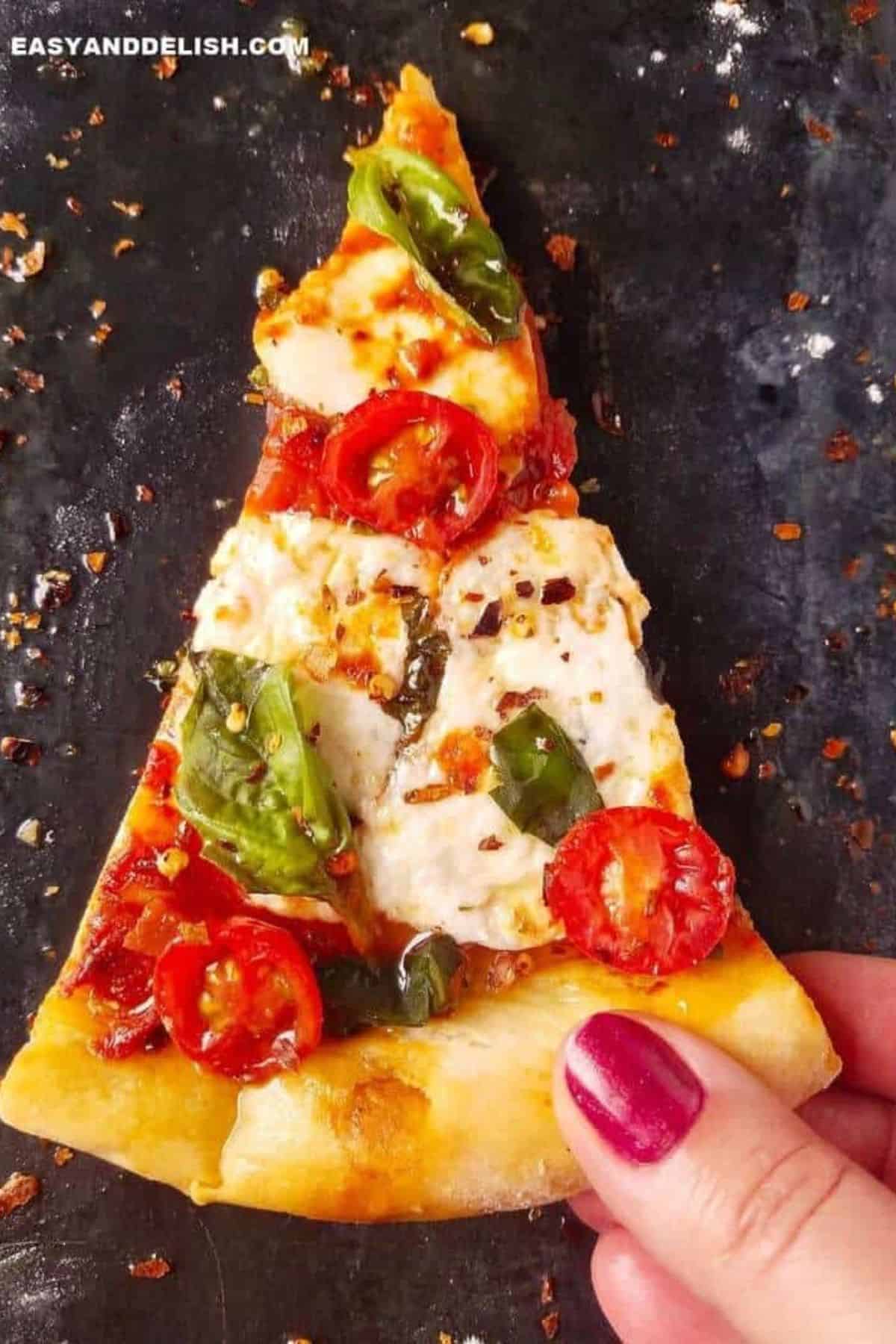 Sliced pizza with fresh mozzarella, tomato sauce, basil, and cherry tomatoes.