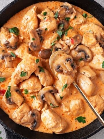 Creamy Brazilian chicken stroganoff with mushrooms and parsley in a cast-iron skillet.