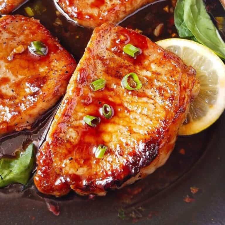 Pan-seared pork chops coated in teriyaki glaze with green onions and lemon slices.