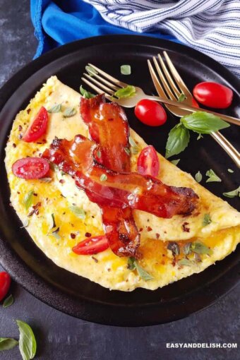 omelete simples em um prato com queijo, bacon e verduras