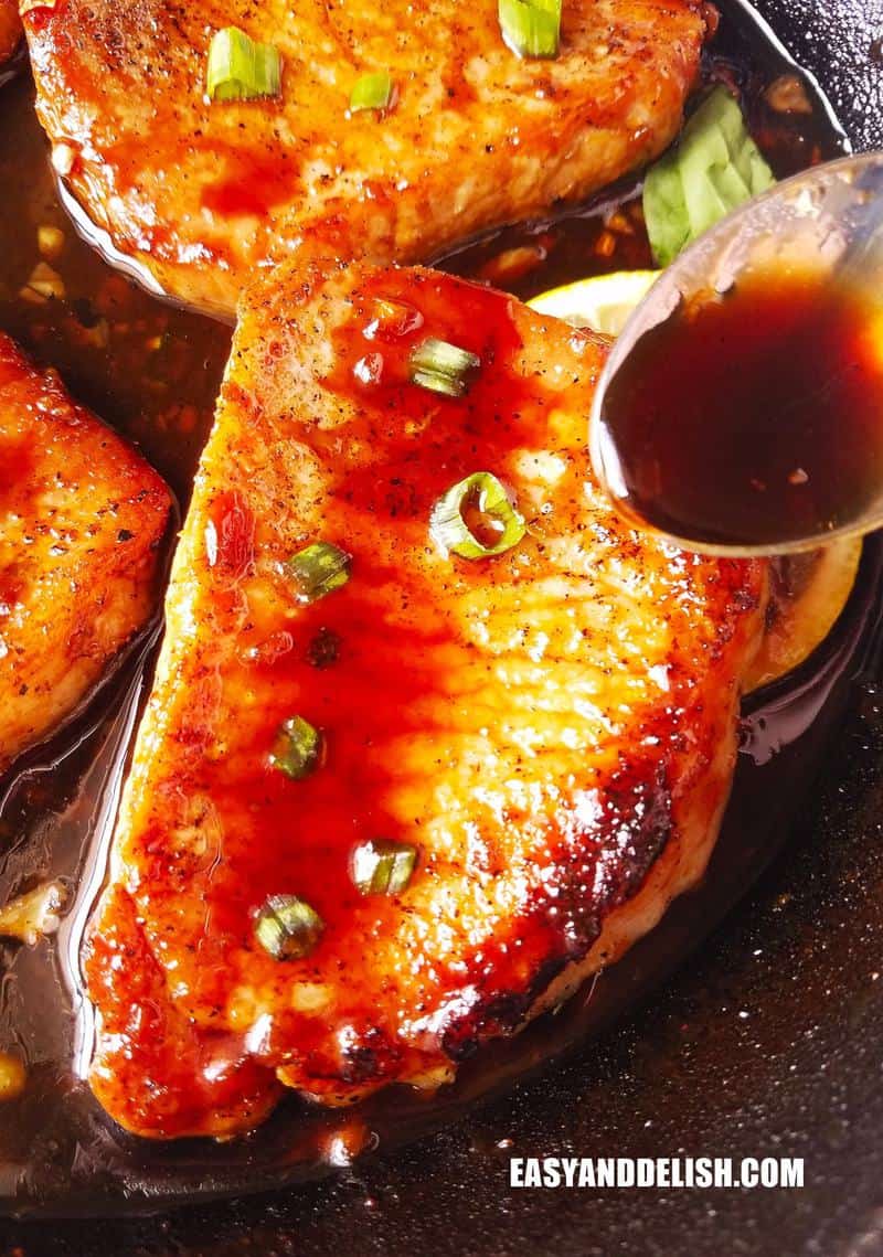 close up image of pan-seared pork chops about to be drizzled with sauce