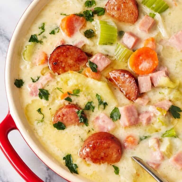 Creamy soup with diced ham, browned sausage, and vegetables in a Dutch oven.
