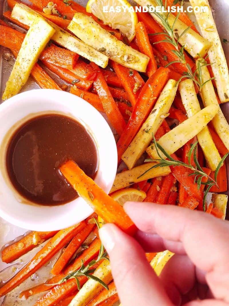 roasted carrots and parsnips being dipped in honey mustard dressing