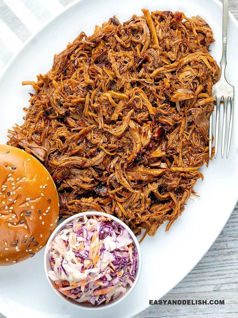 Pressure cooker pulled pork in a platter with coleslaw and bread buns