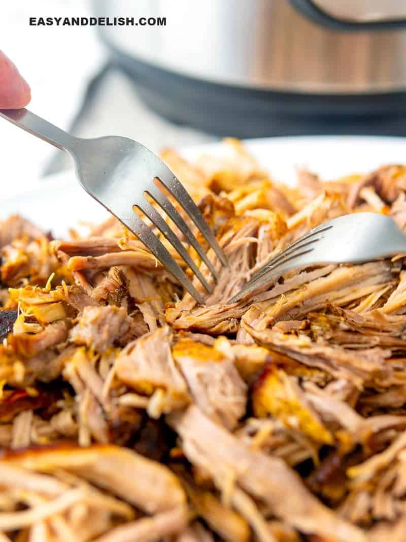 pork being shredded with 2 forks