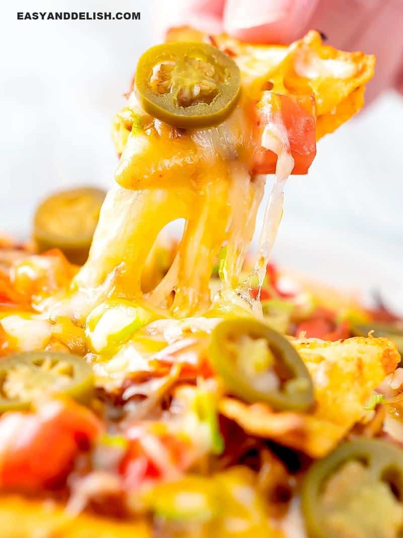 Nachos being pulled up with melted cheese