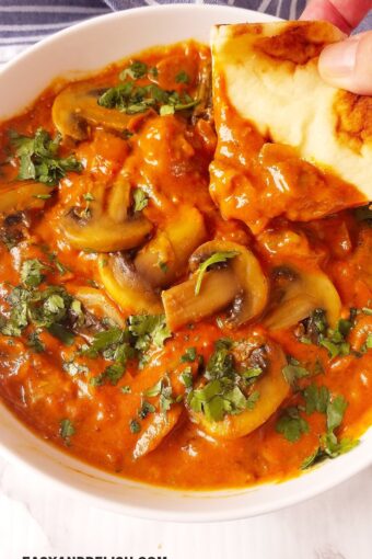 mushroom curry in a bowl with pita being dipped in