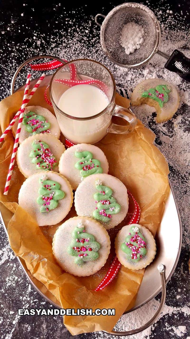 cookies decorado de natal em um prato com uma xícara de leite ao lado