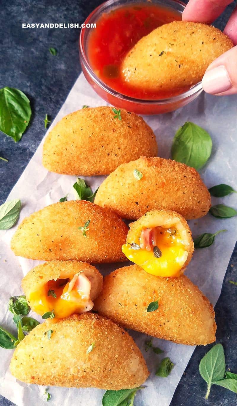 rissoles being dipped in a bowl of sauce 