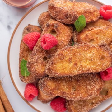 um prato com um monte de rabanada, frutas vermelhas, e mel ao lado