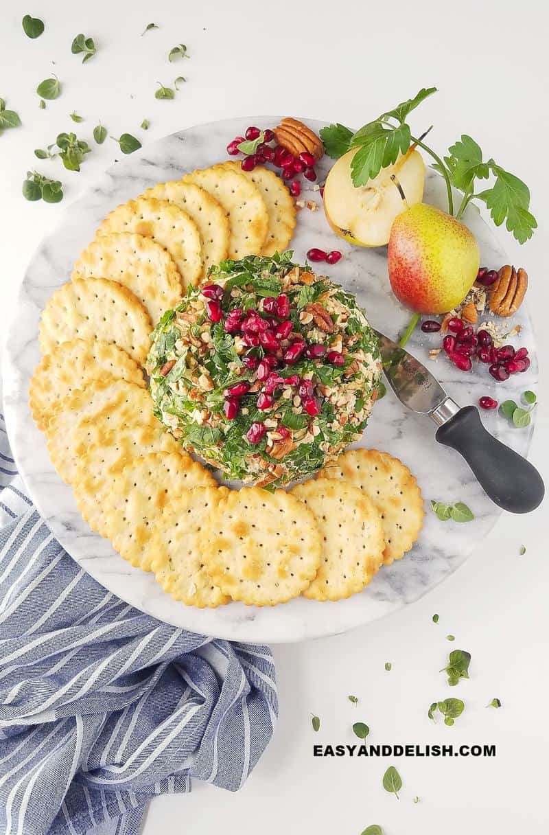 a platter with a cheese ball and crackers plus fruits