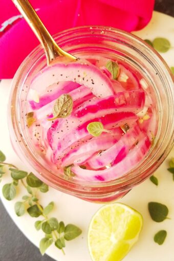 pikled red onions in a jar with garnishes on the side