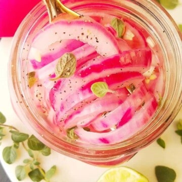pikled red onions in a jar with garnishes on the side