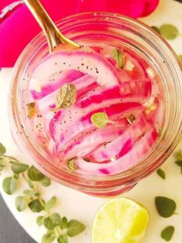 pikled red onions in a jar with garnishes on the side