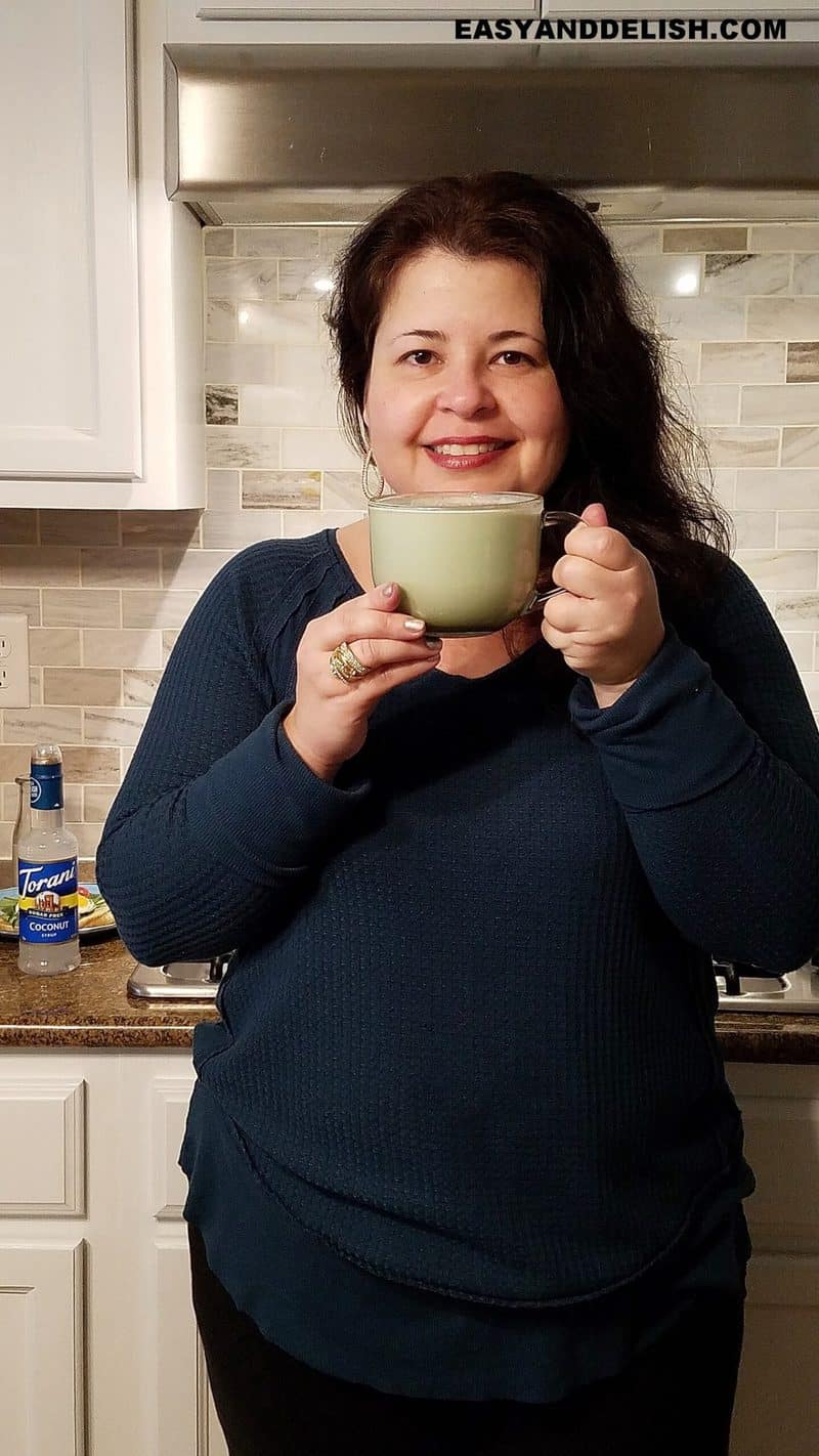 Denise holding a cup of matcha latte in her kitchen