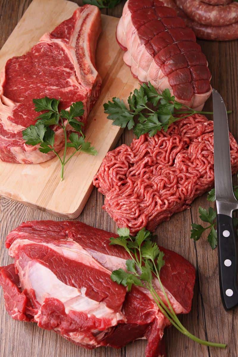 several cuts of meats or steaks on a surface