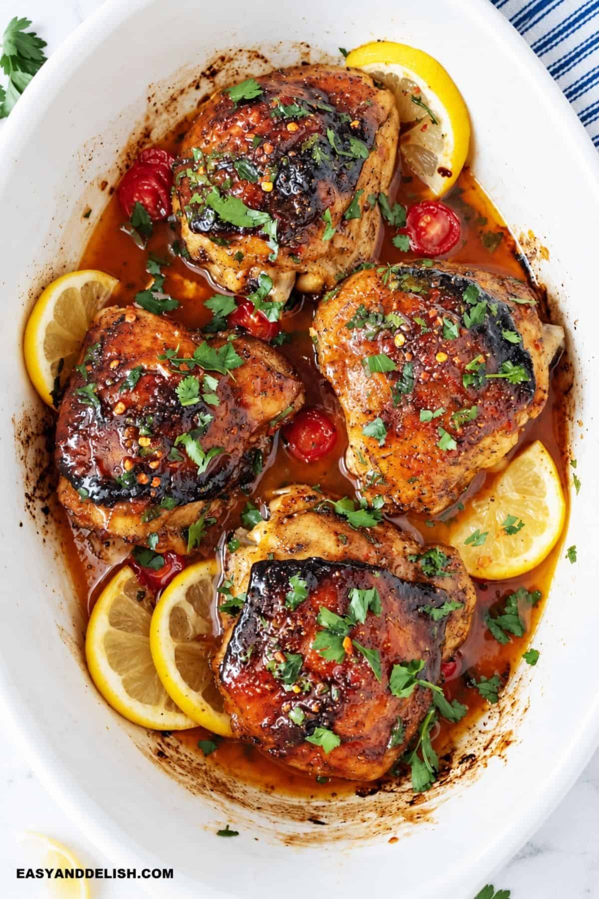 Crispy baked chicken thighs with lemon slices and cherry tomatoes.