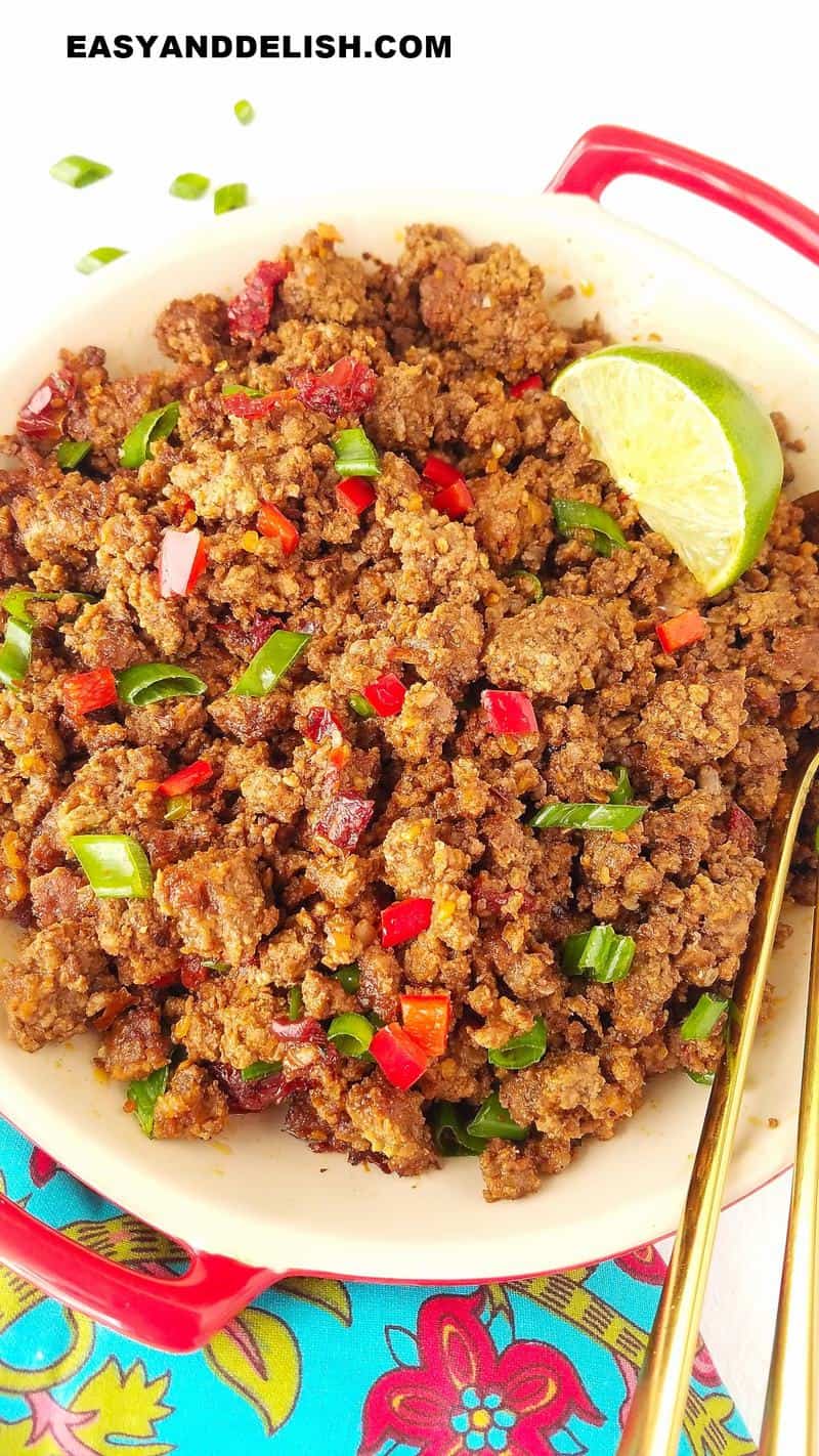 close up of a bowl of cooked ground beef topped with herbs and a lime wedge