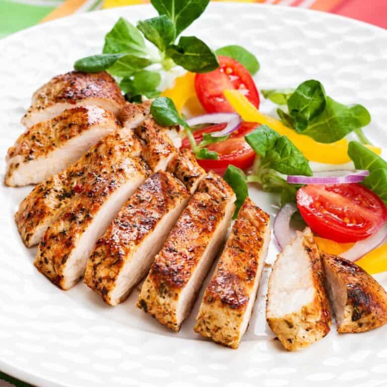 Sliced seasoned chicken breast served with tomatoes, greens, onion, and yellow bell pepper.