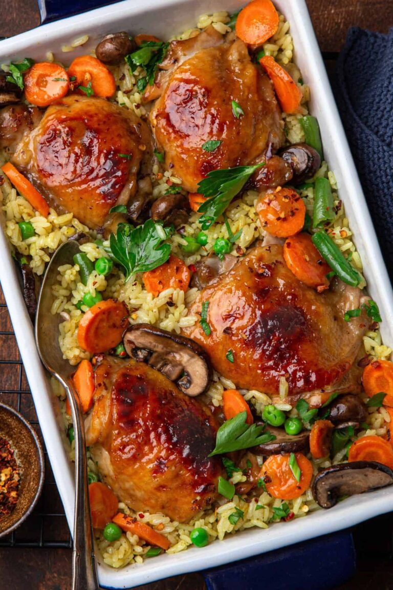 Sobrecoxas de frango assadas com legumes e grãos em assadeira.