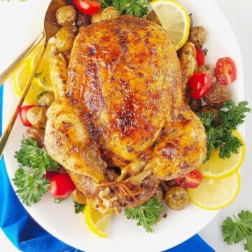frango inteiro na panela de pressão servido em um prato com verduras ao lado