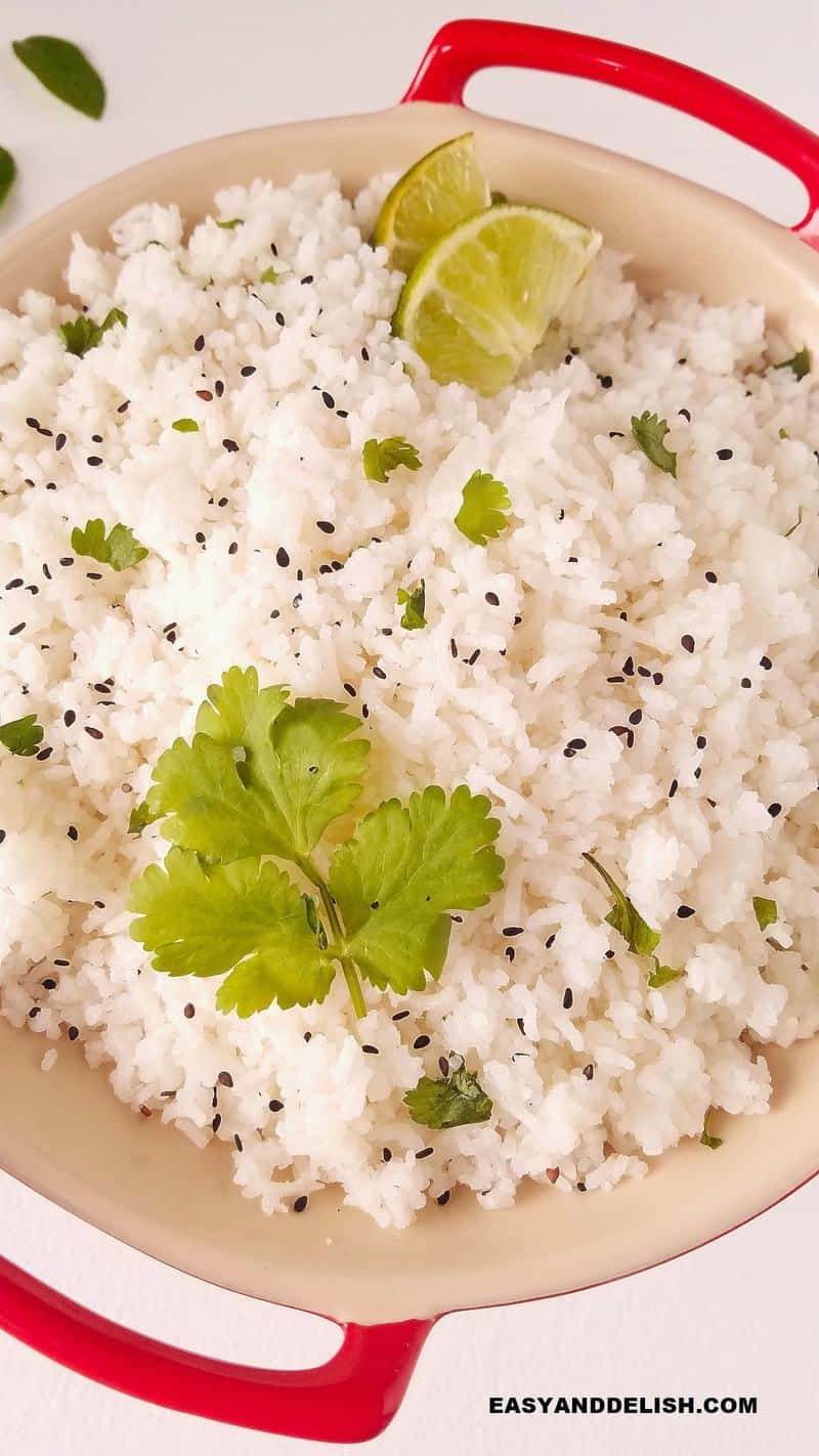 close up of the cooked grain in a bowl topped with cilantro, sesame seeds, and lime wedges