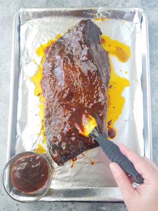 carne cozinhada na panela de pressão sendo pincelada com molho barbecue