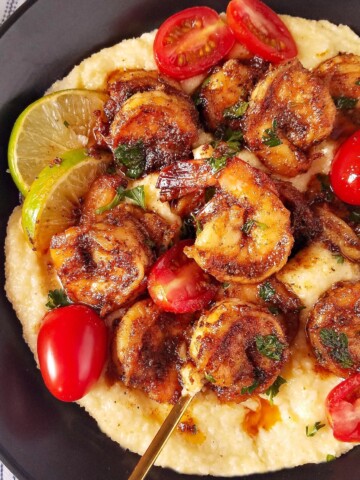 close up image showing a bowl with blackened shrimp over grits