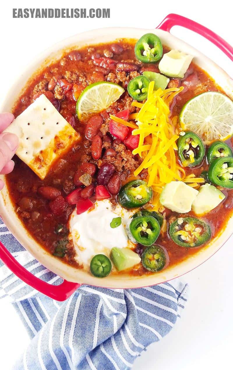 a bowl of chili with a cracked being dipped in it