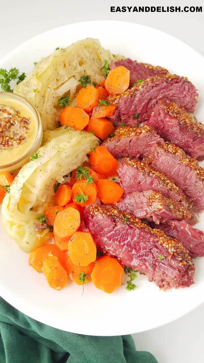 a platter with sliced corned beef and cabbage plus carrots