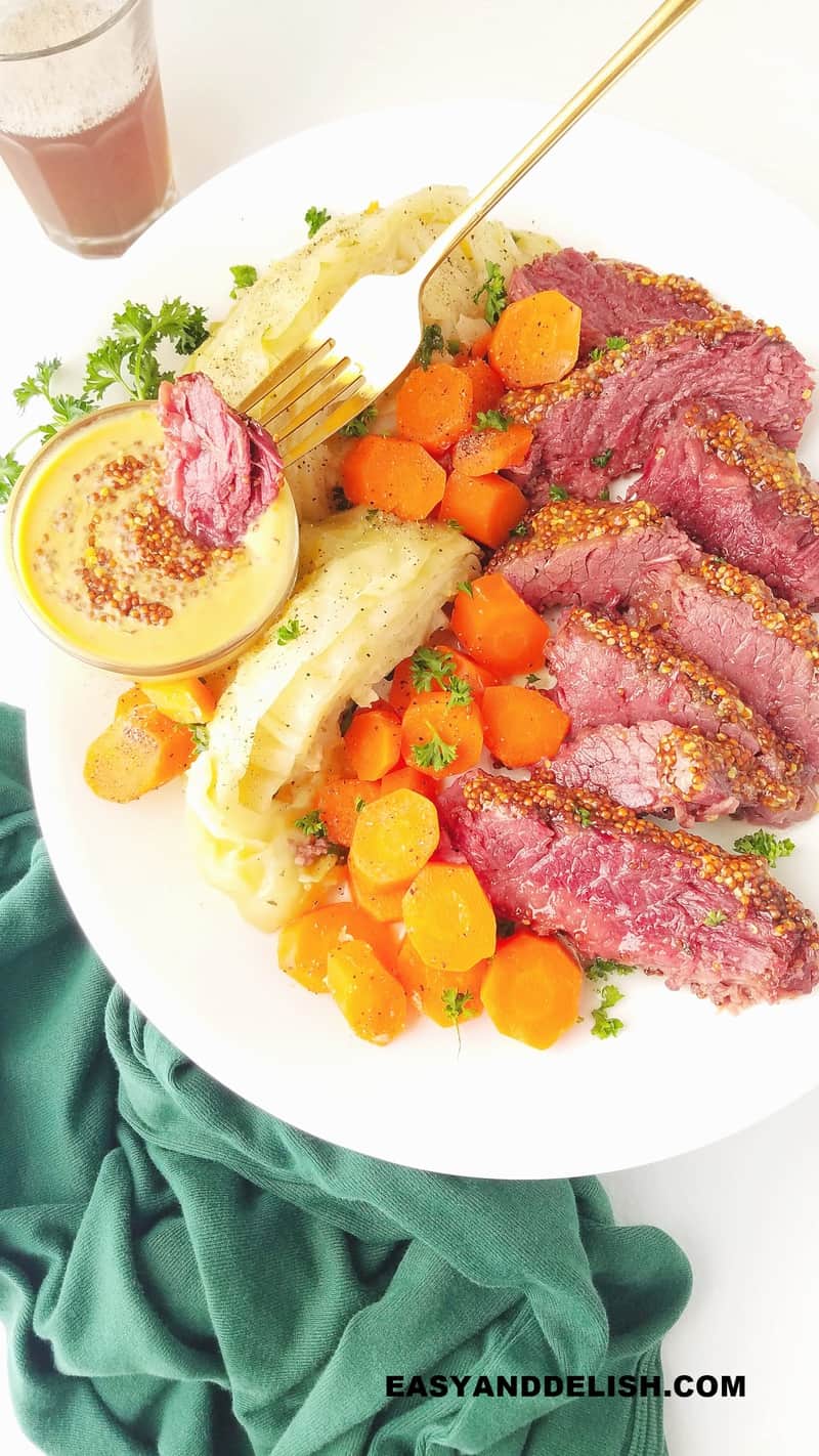 a piece of corned beef being dipped into a mustard sauce