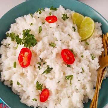 A plate of rice topped with lime and hot peppers