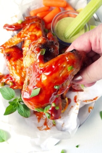 a hand holding a bbq chicken wing cooked in the air fryer