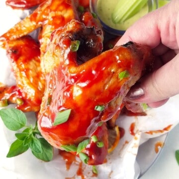 a hand holding a bbq chicken wing cooked in the air fryer